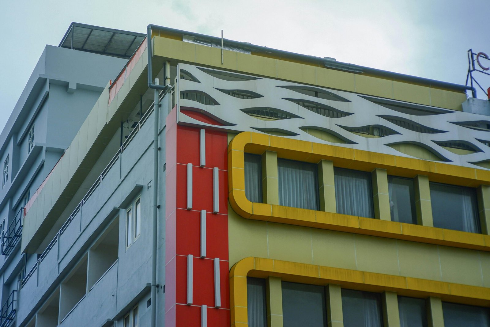 Close-up of a modern building facade featuring red, yellow, and white elements in an urban setting.